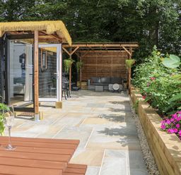 A garden with a cabin, outdoor seating, and plants at Charltons Hollow Cabin in Haywards Heath