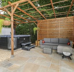 An outdoor area with a hot tub and a sofa at Charltons Hollow Cabin in Haywards Heath