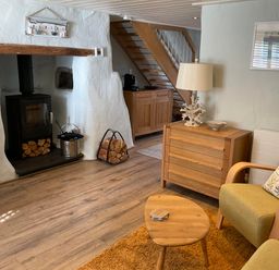 A living room with a fireplace and sofa at Tamarisk Cottage, St Agnes
