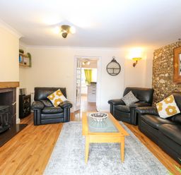 A living room with leather sofas and a coffee table at Honeysuckle Cottage in Swaffham