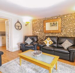 A living room with sofa and table at Honeysuckle Cottage in Swaffham
