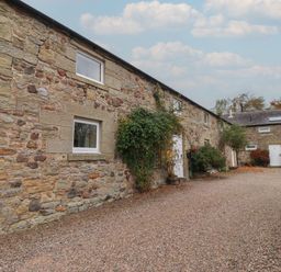 An outdoor view of stone buildings with plants at Honeymug in Branton near Powburn