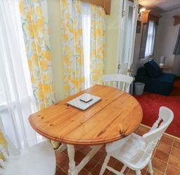 A dining area with a round wooden table and chairs at Static Caravan