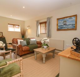 A living room with a sofa, armchairs, and a table at The Annex in Burford