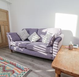 A living room with a purple sofa and wooden table at 1 Castle Terrace