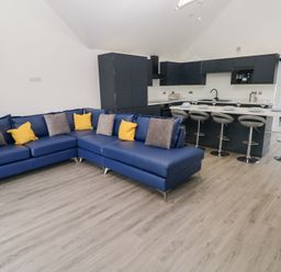 A living room with a sofa and kitchen area at Cottage 1 in Laugharne