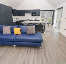 A living room with blue sofa and kitchen area at Cottage 1 in Laugharne