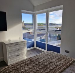 A bedroom with a television and chest of drawers at Milkwood Villa in Laugharne