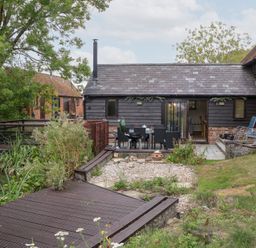 An outdoor area with a wooden deck and a table and chairs at WEST LODGE in Ashford