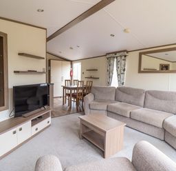 A living room with a sofa and dining table at Beach Retreat E19 Dyffryn Seaside Estate Dyffryn Ardudwy