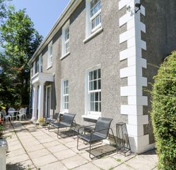A house exterior with seating area and table at Ty Caredig in Swansea