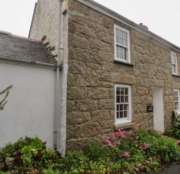 An exterior view of a stone cottage with a garden at 1 Rowes Cottages in Penzance