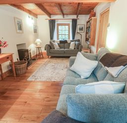 A living room with a sofa and table at 1 Rowes Cottages in Penzance