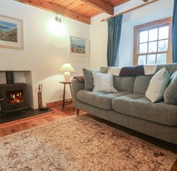 A living room with a sofa and fireplace at 1 Rowes Cottages Penzance