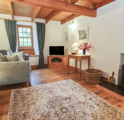A living room with a sofa, television, and a fireplace at 1 Rowes Cottages Penzance