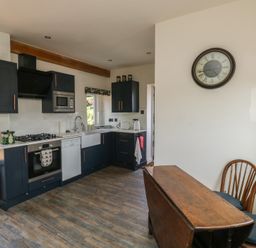 A kitchen with cabinets, stove, sink, and dining area at 13 School Road in Newton Abbot