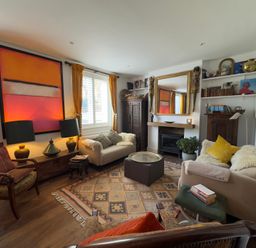 A living room with a sofa, armchair and fireplace at Bohemian Beach Cottage in Bournemouth