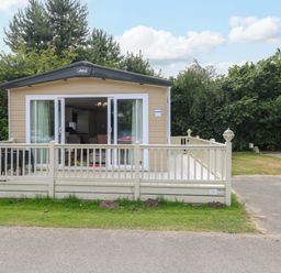 A park home with decking and trees at 17 Castle Walk in Great Yarmouth