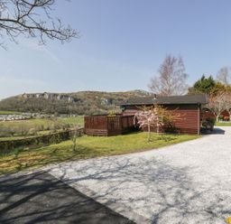 An outdoor area with a lodge and landscaping at Alpine Lodge in Rhyd-y-Foel near Abergele