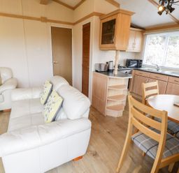 A living room with a sofa and dining area at Alpine Lodge in Rhyd-y-Foel near Abergele