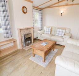 A living room with a sofa and coffee table at Alpine Lodge Rhyd-y-Foel near Abergele