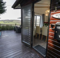 An outdoor deck with seating and a table at Springtime Lodge Rhyd-y-Foel near Abergele