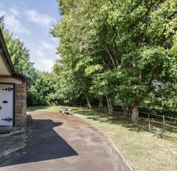 An outdoor area with a bench and trees at Raglan Lodge in Monmouth