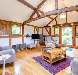 A living room with wooden beams two armchairs a coffee table and a television at The Cider Mill in Westhope near Leominster