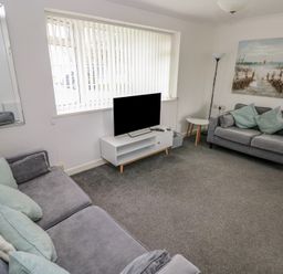 A living room with a sofa and television at Chalet 26 in Scurlage