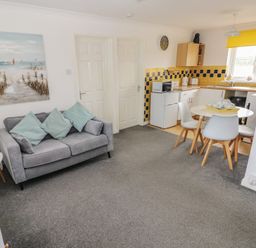 A living room with a couch and a kitchen area at Chalet 26 in Scurlage