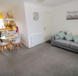 A living room with a dining area and kitchen in Chalet 26 Scurlage