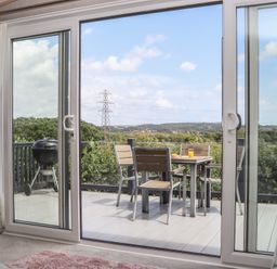 A patio with a table and chairs overlooking the countryside at Maple Lodge in Teigngrace near Kingsteignton