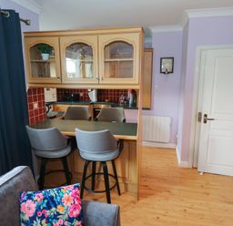 A kitchen with bar stools and cabinets at Kathleens Cosy Apartment in Galway