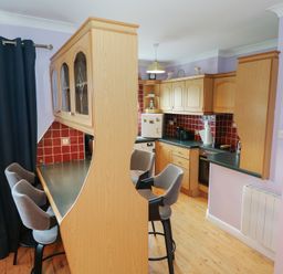 A kitchen with bar stools and cabinets at Kathleens Cosy Apartment in Galway