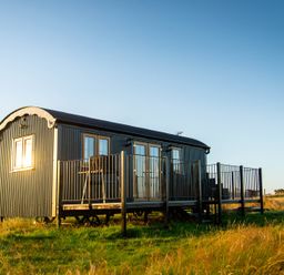 A shepherd's hut with a deck and handrails at Head For the Hills Glamping - Skylark Shepherd's Hut