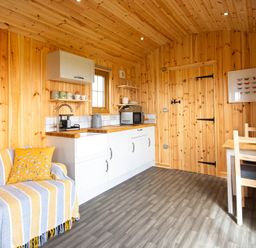 A kitchen with wooden walls and a table at Head For the Hills Glamping - Skylark Shepherd's Hut