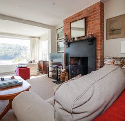 A living room with a fireplace and television at Kiln Cottage in Golant near Tywardreath