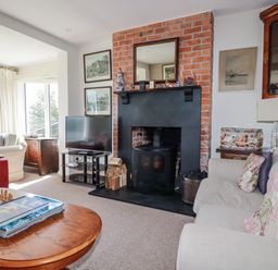 A living room with a fireplace and television at Kiln Cottage in Golant near Tywardreath