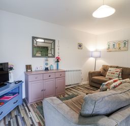 A living room with a television, sofa, and various decorative items at Manorcombe 21 near Honicombe Holiday Village