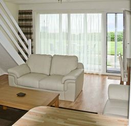 A living room with two beige sofas a wooden coffee table sat by glass doors at Seascape in Kessingland near Lowestoft