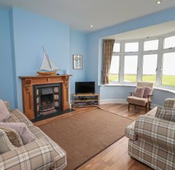 A living room with a fireplace and television at Glen Avon in Seahouses