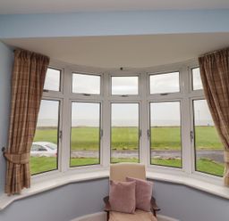 A sitting room with a view of a grassy area outside at Glen Avon in Seahouses