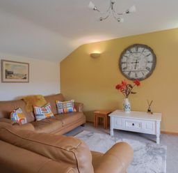 A living room with a sofa and clock at The Granary in Wyke Nr Axminster