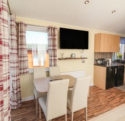A kitchen with dining table and chairs at Cody Cottage Lodge Mullacott Park near Ilfracombe