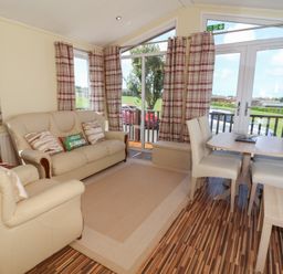 A living room with a sofa and dining area at Cody Cottage Lodge near Mullacott Park