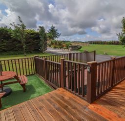 An outdoor seating area with a wooden table in the garden at Cody Cottage Lodge Mullacott Park near Ilfracombe