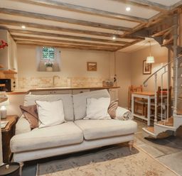 A living room with a sofa and kitchenette at Woodedge in Porlock