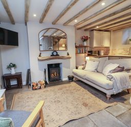 A living room with a fireplace and sofa at Woodedge in Porlock