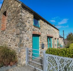 An exterior view of a stone building with teal doors at The Barn in Newport