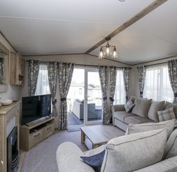 A living room featuring a sofa, television, and coffee table at Grasmoor View Lodge